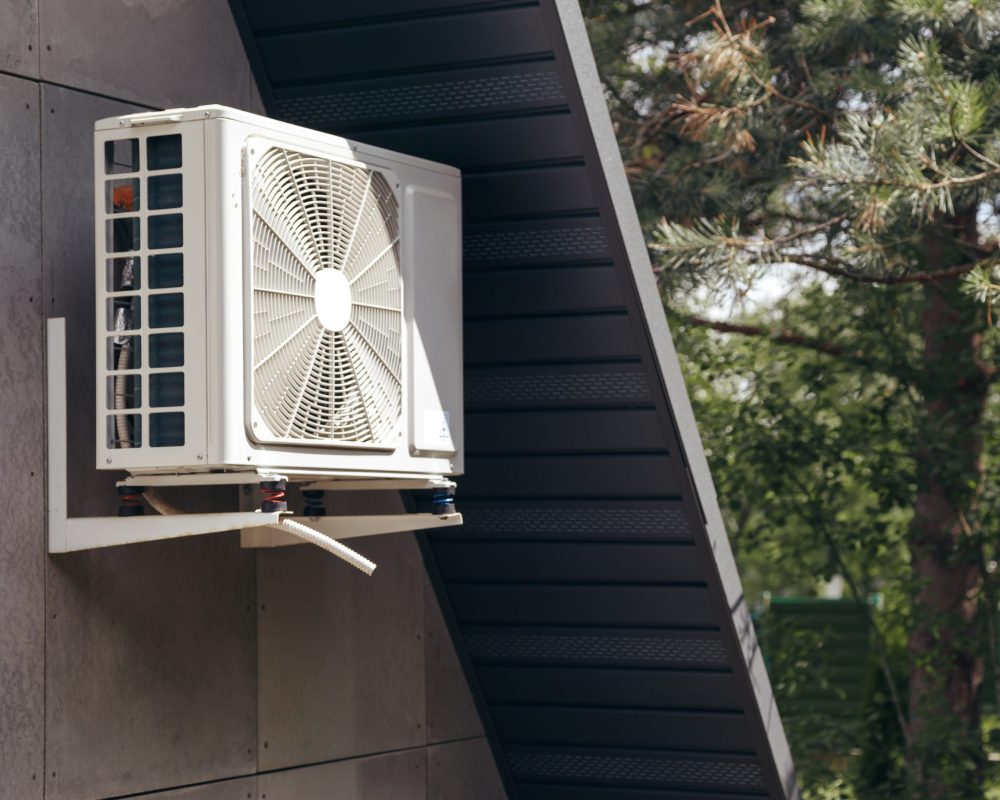 External unit of an air conditioner on facade of small wooden forest house